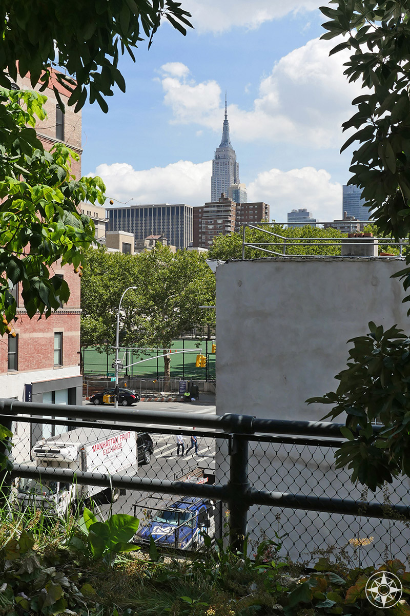 View of the Empire State Building between the trees of the elevated park The High Line. Happier Place