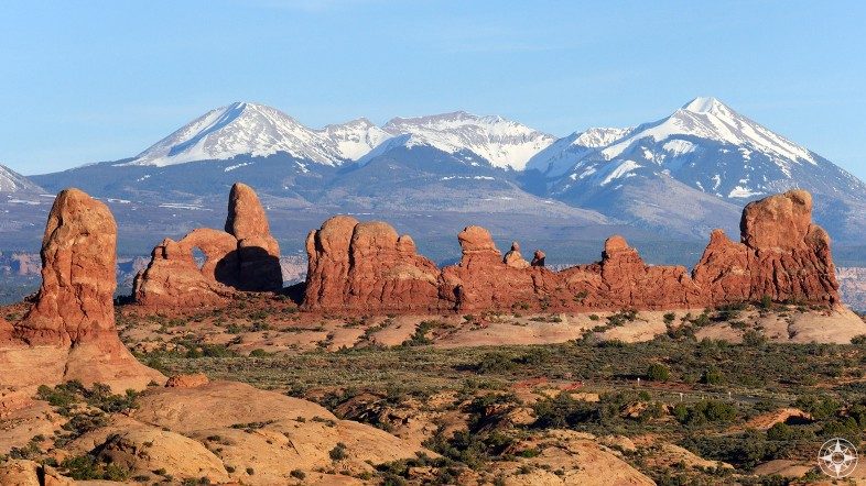 Turret Arch and other rock formation in front of the snow-covered La Sal Mountains in Utah.