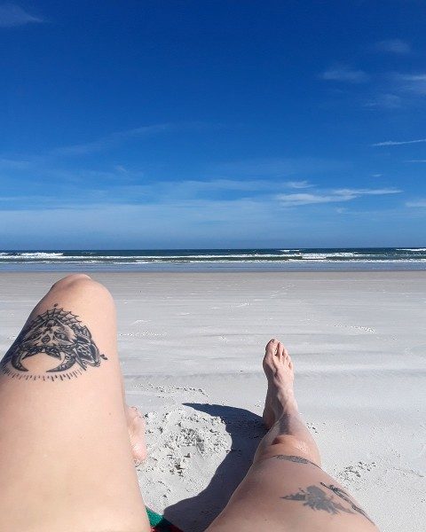 Tattooed legs on a Florida beach.
