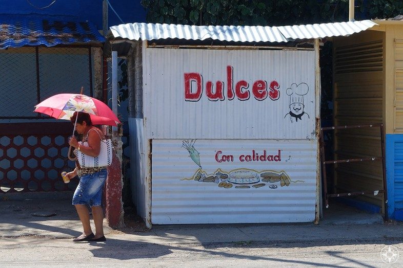 Dulces Con Calidad - Quality Sweets hut in La Boca Cuba and woman using umbrella for shade.