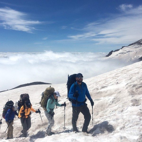 Jake Gray leading a group up snowy Mount Rainier above the clouds
