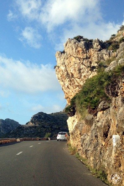 Winding road with rock overhang in the Driving through the Tramuntana Mountain on a road lined by rustic walls