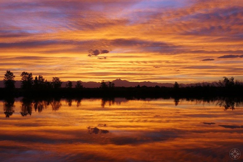 Colorado sunset reflected in pond with Rocky Mountains backdrop