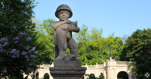 Statue of boy holding fish at Maerchenbrunnen Fairy Tale Fountain in Volkspark Friedrichshain Berlin