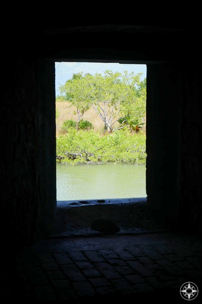 View through a window of Fort Taylor to the moat and plant life beyond.