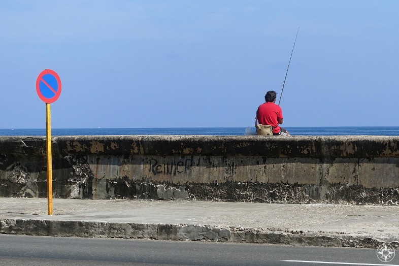 Red and blue traffic sign, man fishing and the sky - Maleón wall, Havana