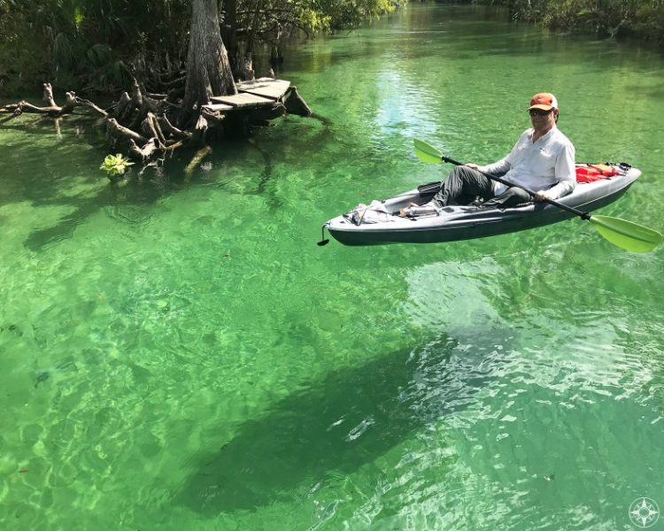 Kayak floating above its shadow on white sand in the clear water of Weeki Wachee River